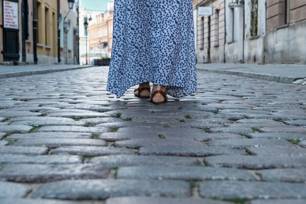 Weibliche Beine in Sandalen gehen auf den Kopfsteinpflaster auf einer Stadtstraße