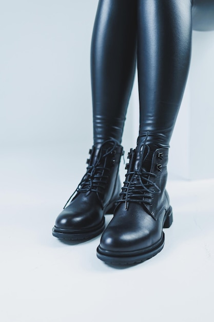 Weibliche Beine in schwarzen Herbststiefeln aus Leder Ein Modemädchen steht in einem Geschäft und misst Schuhe