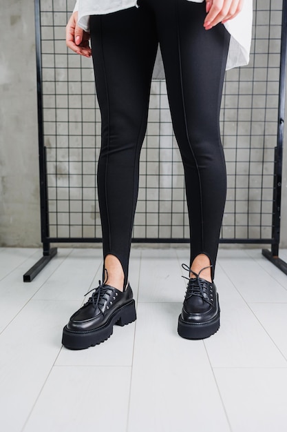 Weibliche Beine in trendigen schwarzen Leggings und Loafers Schnürsenkel auf Lederschuhen Details eines stilvollen Herbstmode-Looks