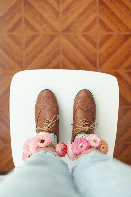 Weibliche Beine mit Blumen auf Socken und Vintage-Schuhen auf altem Stuhl