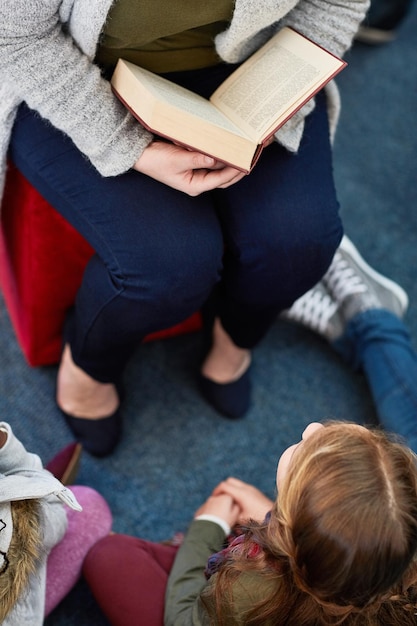 Weibliche Beine und Buchlesen für Kinder in der Bibliothek Bildung und Fantasie Literatur Fiktion Weibliche Person Lehrerin und Top-View des Geschichtenerzählens Roman Englischwissen und Sprachentwicklung