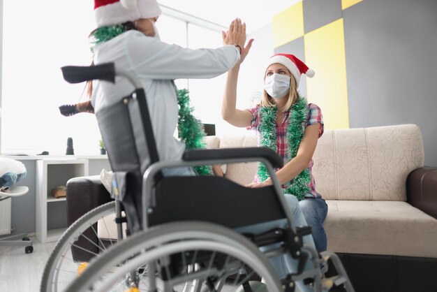 Weibliche Besuchsschwester in einer Klinikverwandten, die im Rollstuhl sitzt und High Five gibt