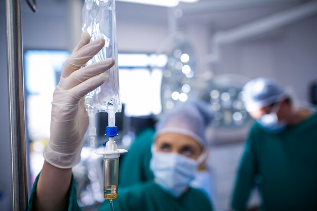 Weibliche Chirurgen, die iv Tropf im Operationssaal einstellen