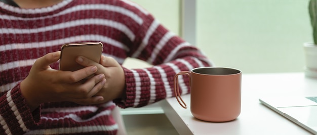 Weibliche Entspannung von der Arbeit mit Smartphone und Kaffee auf weißem Arbeitstisch