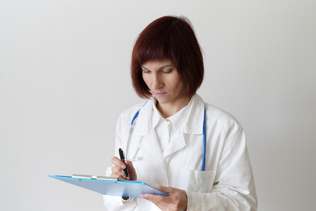 Weibliche erwachsene Ärztin steht auf weiß
