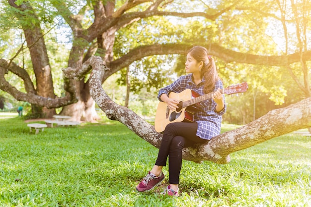 Weibliche Finger, welche die Gitarre im Freien im Sommerpark spielen.