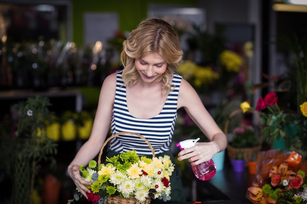 Weibliche Floristen, die Wasser auf Blumen im Blumenladen sprühen