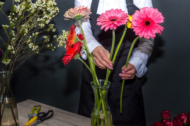 Weibliche Floristin, die in einem Blumenladen einen Blumenstrauß aus Gerberas herstellt