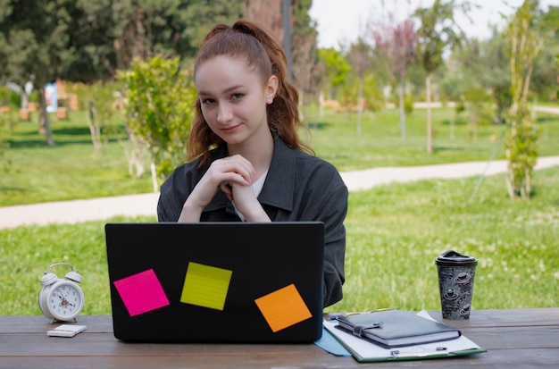 Weibliche freiberufliche Programmiererin, die am Laptop mit Aufklebern im Park arbeitet