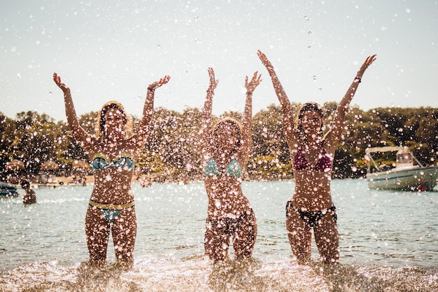Weibliche Freunde spritzen bei Sonnenuntergang Wasser ins Meer