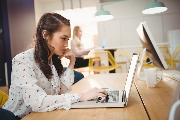 Weibliche Führungskraft, die am Laptop im Büro arbeitet