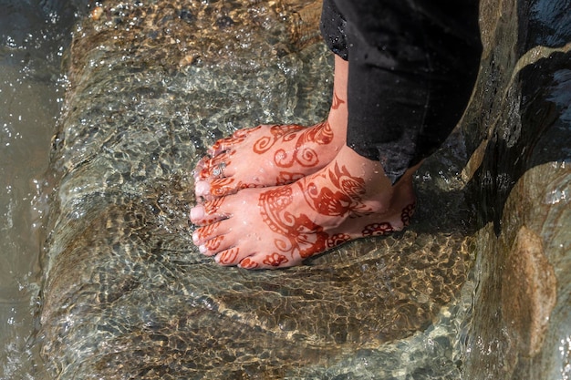 Weibliche Füße im Wasser des Flusses Ganges mit Henna-Tattoo Nahaufnahme Indien