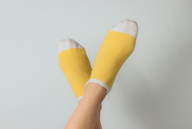 Weibliche Füße mit gelben Socken auf weißem Hintergrund