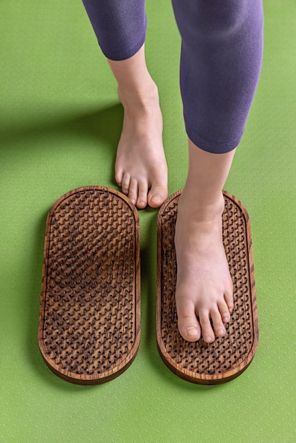 Weibliche Füße stehen auf einem Sadhu-Brett mit Nägeln auf einer grünen Matte Yoga-Praxis hautnah