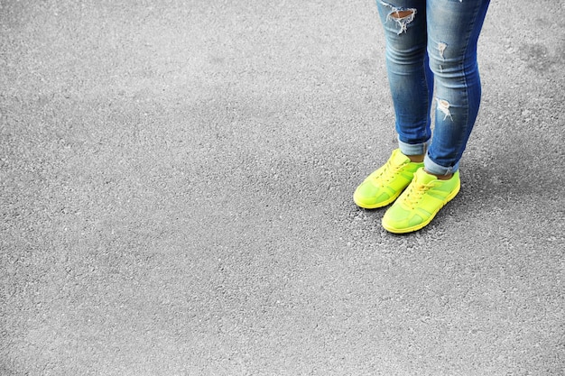 Foto weibliche füße über grauem asphalthintergrund