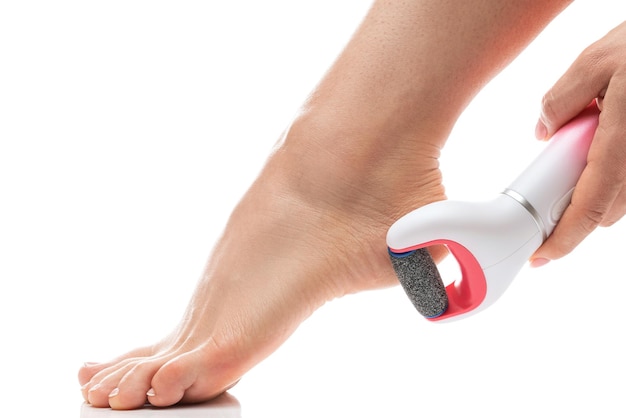 Weibliche Füße und elektrische Fußfeile zur Entfernung von Hornhaut und abgestorbener Haut auf weißem Hintergrund