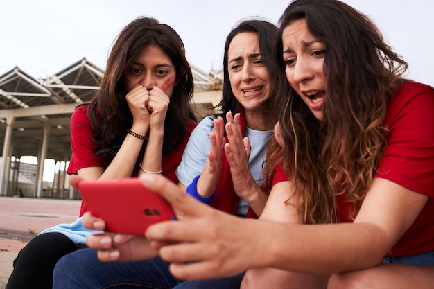 Weibliche Fußballfans, die während des Fußballspiels auf das Telefon schauen