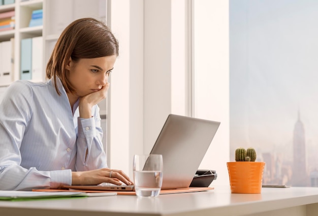 Weibliche Geschäftsführerin sitzt am Schreibtisch und arbeitet mit einem Laptop-Geschäfts- und Kommunikationskonzept