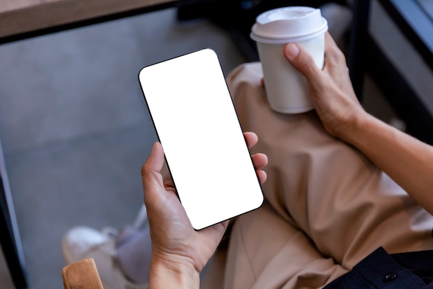 Weibliche Hände der Draufsicht, die Smartphone mit leerem weißem Bildschirm halten