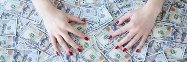 Weibliche Hände, die auf einem Satz von Dollarnoten liegen, Nahaufnahme illegales Gewinnkonzept