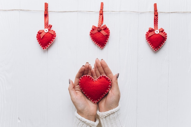 Weibliche Hände, die dekoratives Herz für Valentinstag halten.