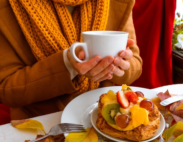 Weibliche Hände, die den weißen Teller mit Kuchen halten