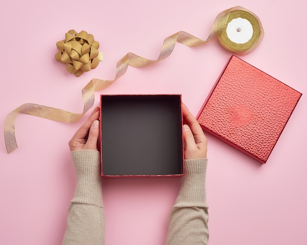 weibliche Hände, die eine quadratische leere Geschenkbox halten