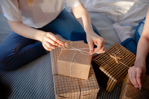 Weibliche Hände, die Geschenk halten. Geschenk Mit Bastelpapier umwickelt. Urlaubskonzept der horizontalen Ansicht von oben.