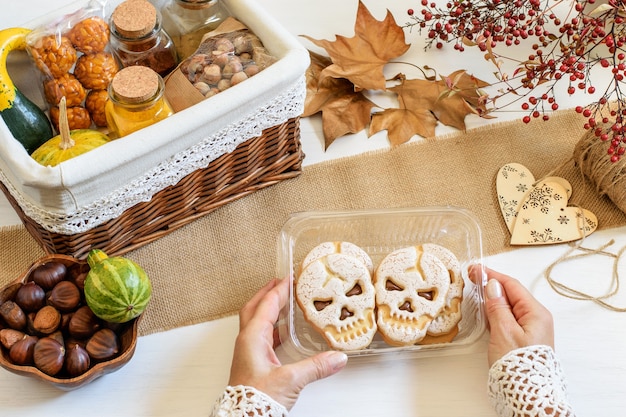 Weibliche Hände, die Halloween-Schädelplätzchen verpacken