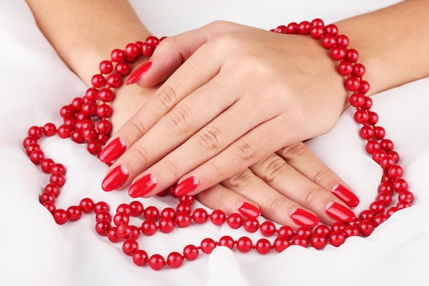 Weibliche Hände, die Perlen auf farbigem Hintergrund halten