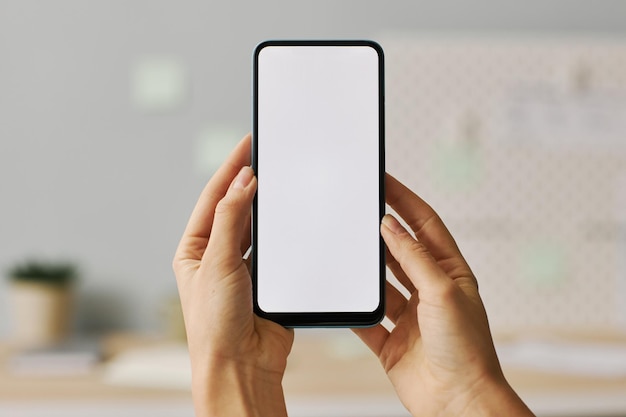 Weibliche Hände, die Smartphone mit weißem Bildschirmspott oben halten