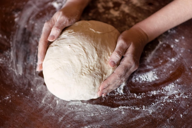 Weibliche Hände, die Teig machen. Teigknetvorgang. Teig auf Basis von Natursauerteig. Weizenteig.