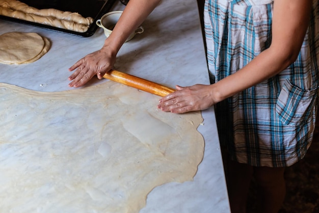 Weibliche Hände, die Teig zum Backen von hausgemachtem Essen zubereiten Konzept des Kochprozesses beim Backen von hausgemachten gerollten Borek-Kuchen