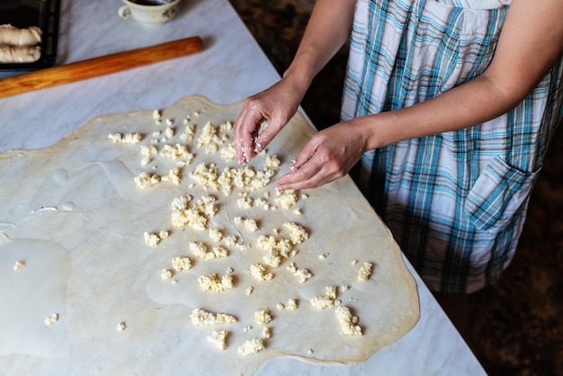 Weibliche Hände, die Teig zum Backen von hausgemachtem Essen zubereiten Konzept des Kochprozesses zum Backen von hausgemachten gerollten Borek-Kuchen