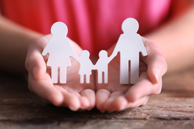 Weibliche Hände, die weiße Familienfiguren halten