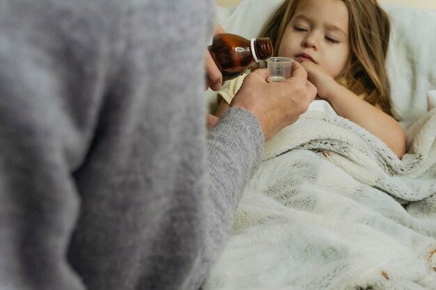 Foto weibliche hände gießen medizin für ein krankes kleines mädchen