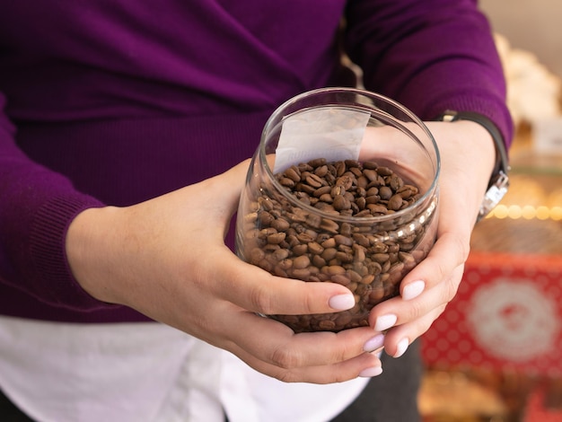 Weibliche Hände halten ein Glas mit Kaffeebohnen Kaffee-Einzelhandelskonzept