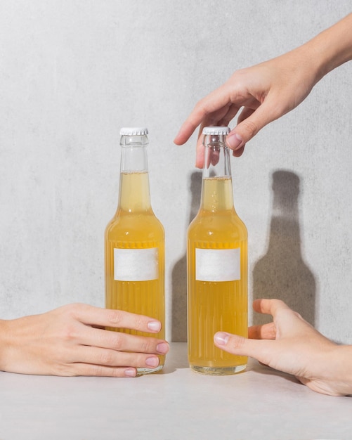 Weibliche Hände halten eine Glasflasche mit leerem Etikett und Flüssigkeit ähnlich wie Limonadenbier Kombucha