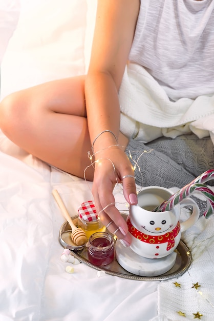 Weibliche Hände halten eine Tasse in Form eines Schneemanns