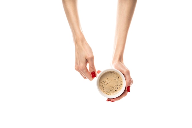 Weibliche Hände halten eine weiße Keramiktasse auf weißem Hintergrund. Kaffeetasse mit Kaffee, Latte, Cappuccino, Threeinone-Kaffee. Weibliche Hände mit frischer roter Maniküre, isoliert auf weißem Hintergrund