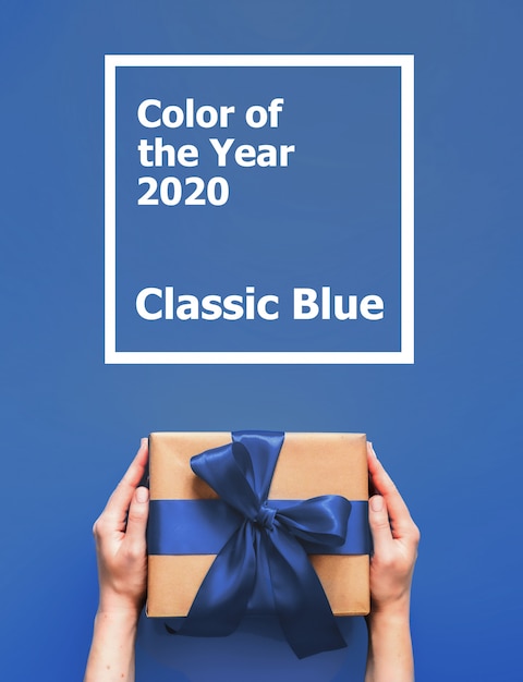 Weibliche Hände halten Geschenkbox mit Wörter Farbe des klassischen Blaus des Jahres 2020.