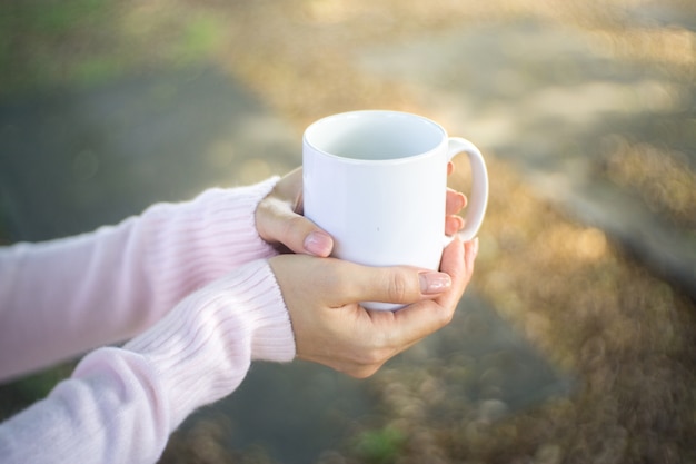 Weibliche Hände halten Tassen Kaffee.