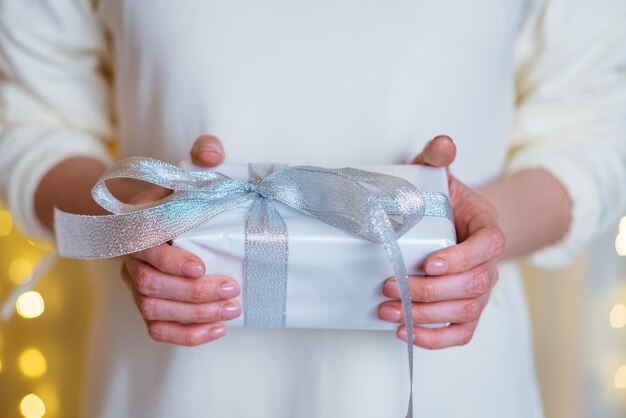 Weibliche Hände halten Weihnachts- oder Neujahrsgeschenkbox auf Boke-Hintergrund Weihnachten Neujahr Geburtstagskonz ...