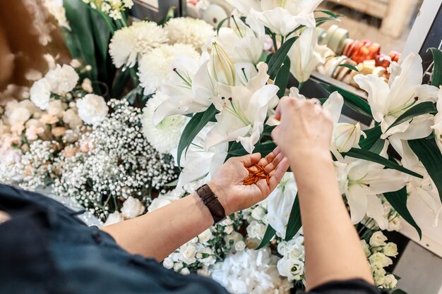 Weibliche Hände kümmern sich um weiße Lilie der Blume. Gartenarbeit und Kleinunternehmenskonzept. Ansicht von oben