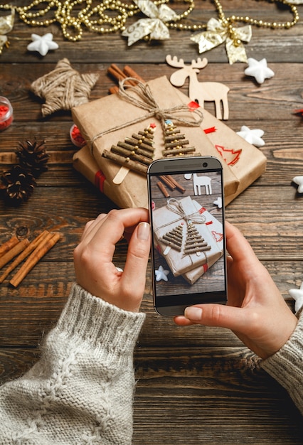 Weibliche Hände machen ein Foto von Weihnachtsaccessoires