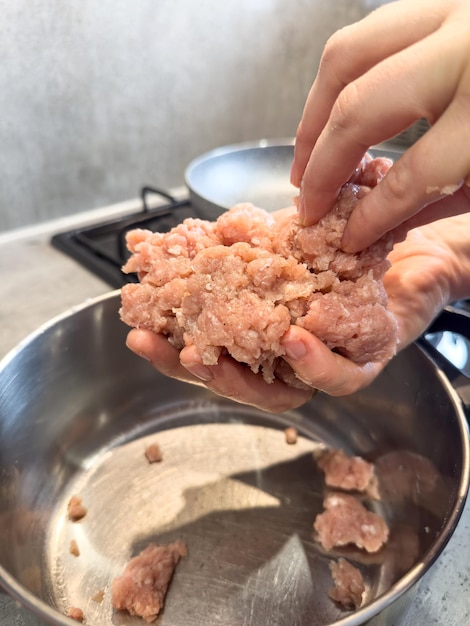 Weibliche Hände machen Fleischbälle mit rotem Fettmince aus der Nähe