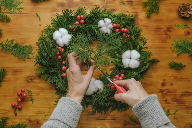 Weibliche Hände machen Weihnachtskranz Overhead-Schuss