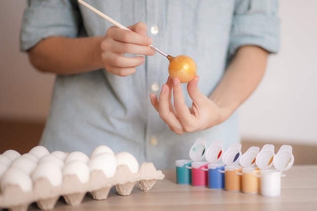 Foto weibliche hände malen ei mit goldfarbe für ostern