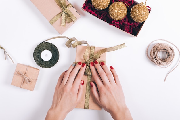 Weibliche Hände mit roten Maniküresatzkästen mit Geschenken