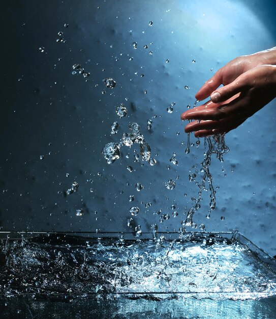 Foto weibliche hände mit spritzendem wasser auf blauem hintergrund